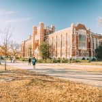 A scenic view of a historic university building surrounded by autumn foliage, reflecting academic architecture.